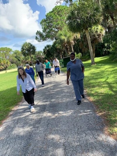 Residents and staff walking on a pathway in a garden