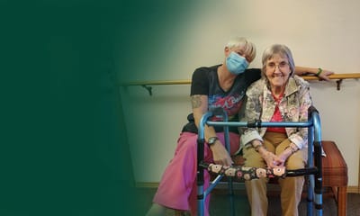 Staff member and resident smiling together in a hallway