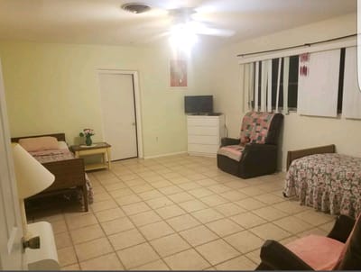 A cozy assisted living room with two beds, a chair, and a TV.