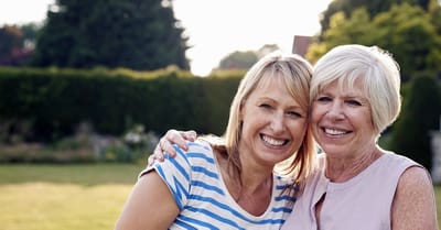 Two women smiling in a garden setting.