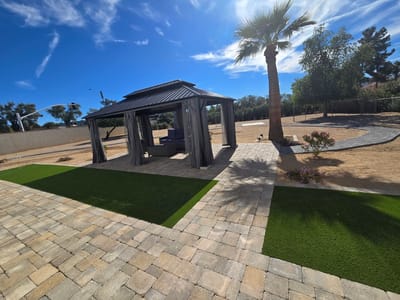 Outdoor gazebo area with palm tree and paved walkway