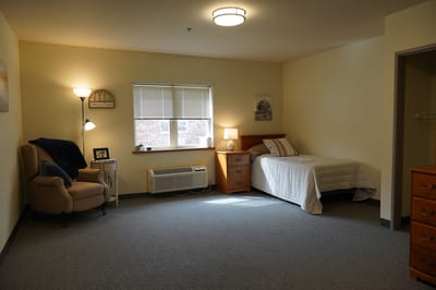 Cozy private room with bed and chair in a corner