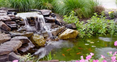 A serene waterfall and pond surrounded by flowers