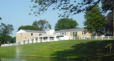 Exterior view of the assisted living facility with a pond and greenery