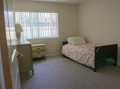 Bright, simple resident room with a bed and dresser