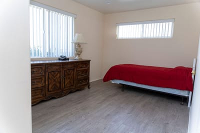 A simple resident room with a bed and dresser