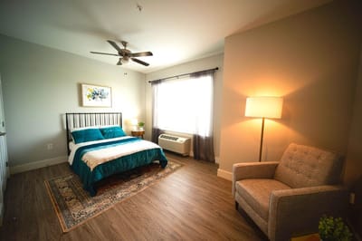 Brightly decorated resident room with a bed and chair