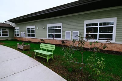 Exterior view of a building with a green bench and landscaping
