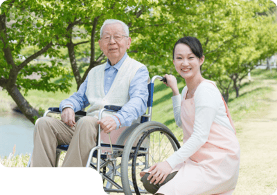 Senior man in a wheelchair with caregiver outside