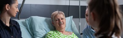 Smiling elderly woman with family at her bedside