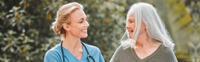 Nurse and resident smiling together outdoors