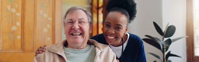 A smiling resident with caregiver in a communal space.
