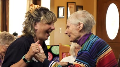Staff and resident sharing a joyful moment during an activity