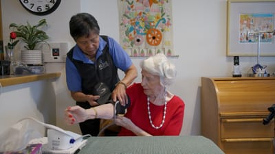 Nurse taking a resident's blood pressure in a common area