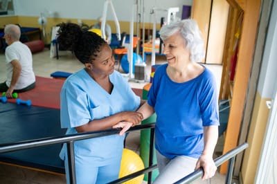 Staff assisting a resident in a therapy area