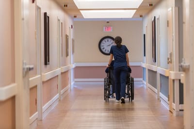 Staff member pushing a resident in a hallway