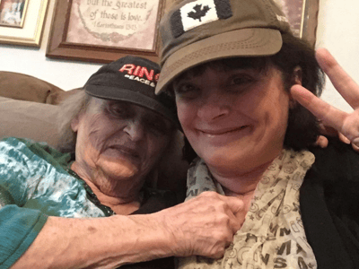 Two women smiling, one elderly and one younger, in a cozy setting