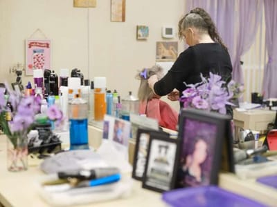Resident receiving hair styling in a salon area
