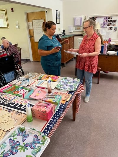 Staff assisting a resident with crafts at a table