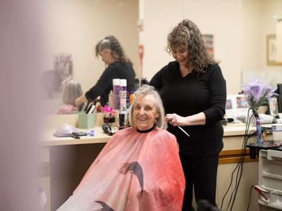 Stylist attending to a smiling resident in a salon