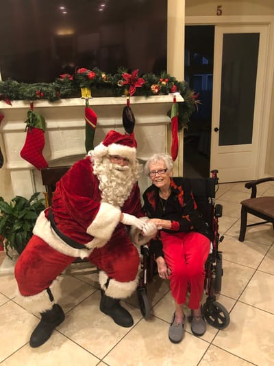 Resident celebrating with Santa Claus in a festive lobby