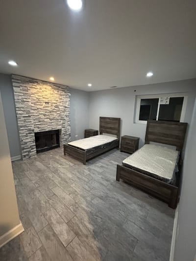 A room with two beds and stone fireplace