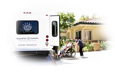 Staff assisting a resident in a wheelchair to a facility vehicle