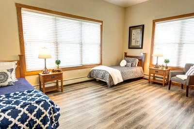 Brightly lit shared bedroom with two beds and wooden furniture