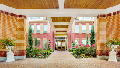 Campanile on Justice Park, independent living in Houston, TX — Entrance to a senior living facility with landscaped gardens