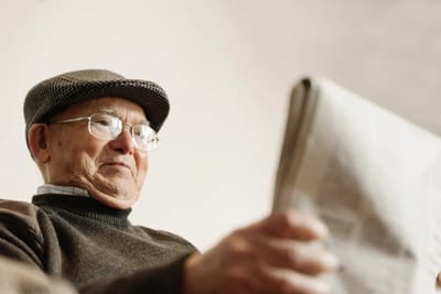 Elderly man reading a newspaper indoors