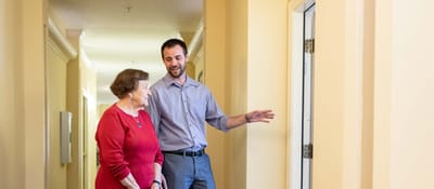 Staff member assisting a resident in a hallway