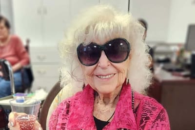 A smiling elderly woman with sunglasses in an indoor setting