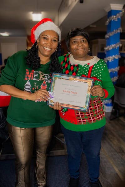 Two women celebrating with a certificate in a festive setting