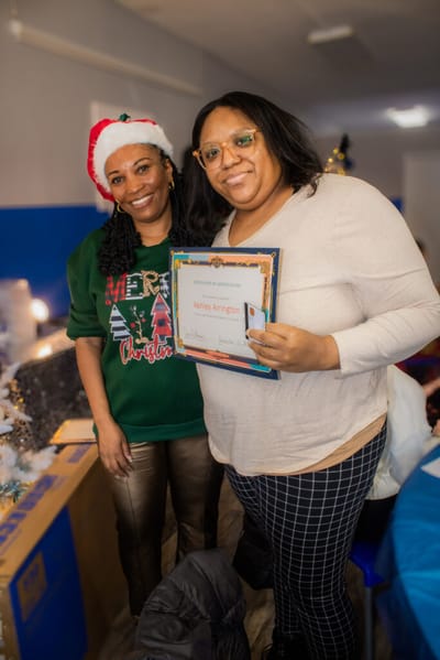 Two women celebrating with an award certificate.