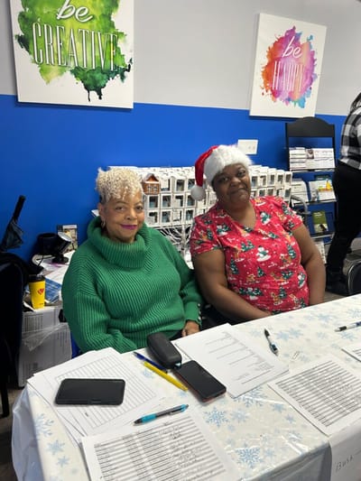 Two women engaged in a festive activity at a table.