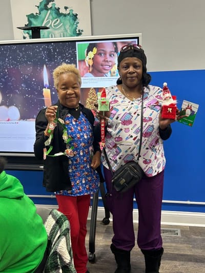 Two staff members holding arts and crafts decorations.