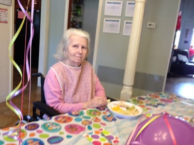 Senior resident enjoying a meal at a festive table.