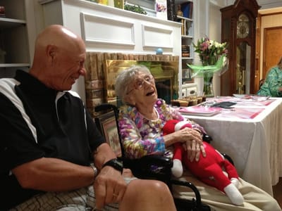Elderly woman happily interacting with a visitor in a common area.