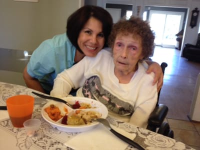 Staff member with elderly resident enjoying a meal.