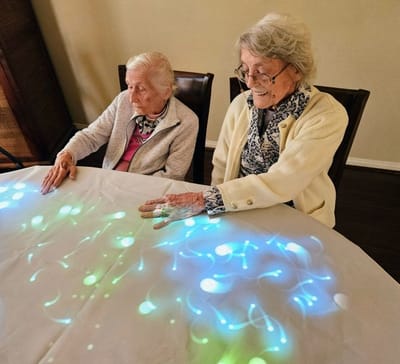 Two elderly women interacting with a sensory table activity.