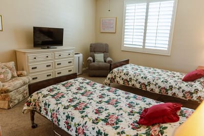 Bright bedroom with floral bedding and TV.