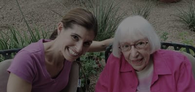 Senior woman and caregiver smiling outdoors