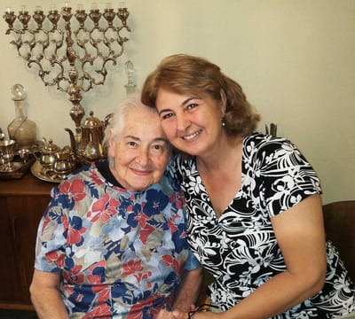 Smiling elderly woman with caregiver in interior setting