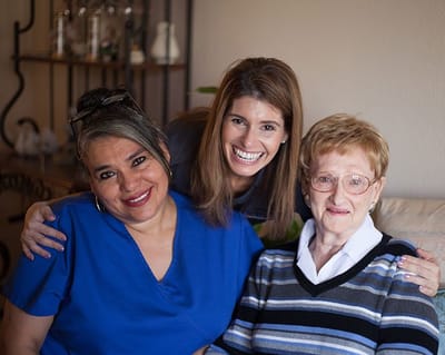 Two caregivers and a resident smiling together.