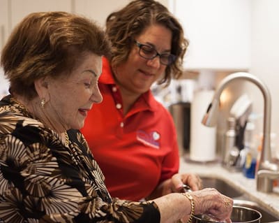 Caregiver and resident cooking together in a kitchen.