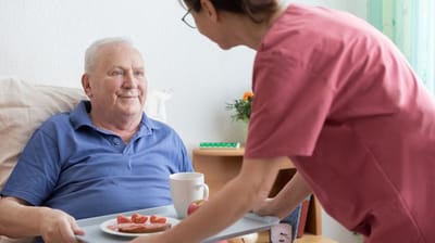 Caregiver serving food to a smiling resident