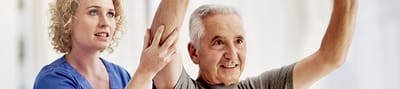 Therapist assisting senior with arm exercises