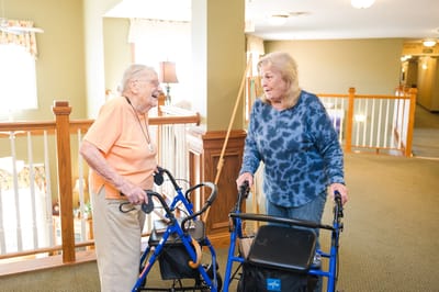 Two elderly women chatting in a hallway