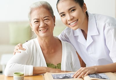 Caregiver smiling with a resident at a table.