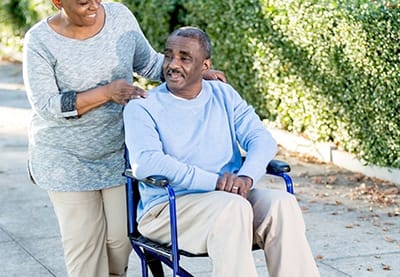 Caregiver assisting a resident in a wheelchair outdoors